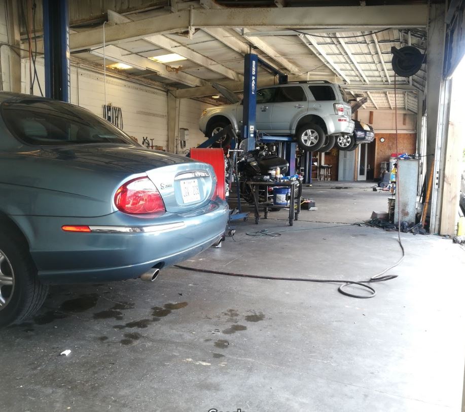 A Jaguar sedan and an SUV on the lift inside the D and M Auto Repair service bays