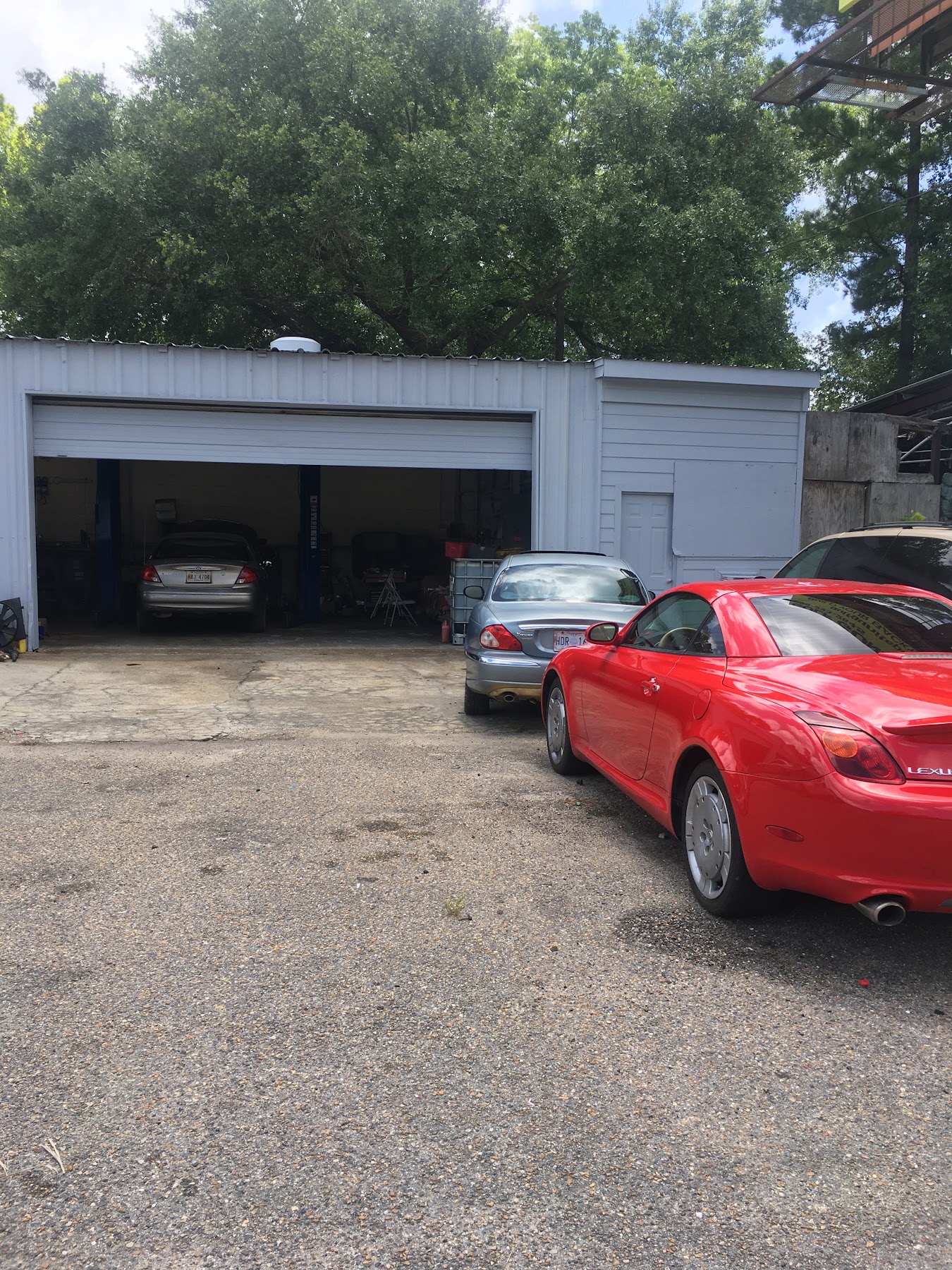A red Lexus convertible parked outside the open service bays at D and M Auto Repair